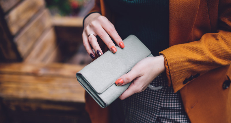 Lähiplaan kätest, mis hoiavad helehalli rahakotti.