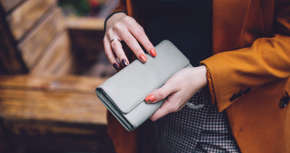 Lähiplaan kätest, mis hoiavad helehalli rahakotti.