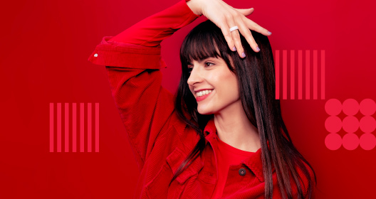 A woman in red clothing raising her hand and displaying a payment ring on her finger.