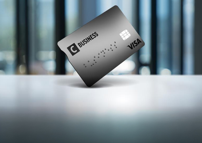 Hall C Business krediitkaart seisab laual püsti, udune moodne kontoritaust.