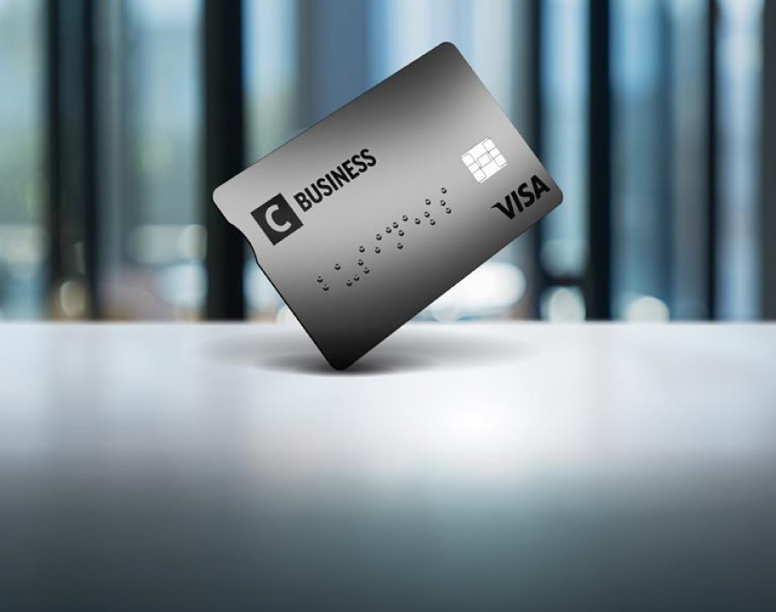 Hall C Business krediitkaart seisab laual püsti, udune moodne kontoritaust.