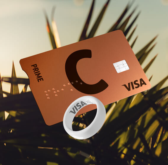 C prime lava VISA pangakaart ja valge maksesõrmus VISA logoga palmilehtede taustal päikeseloojangul.