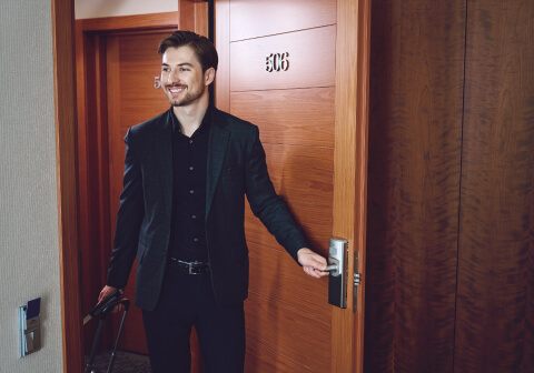A man with a suitcase enters a hotel room, illustrating the travel benefits of C Infinite.
